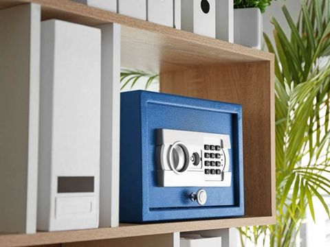 Blauer Tresor und weisse Ordner in einem Regal